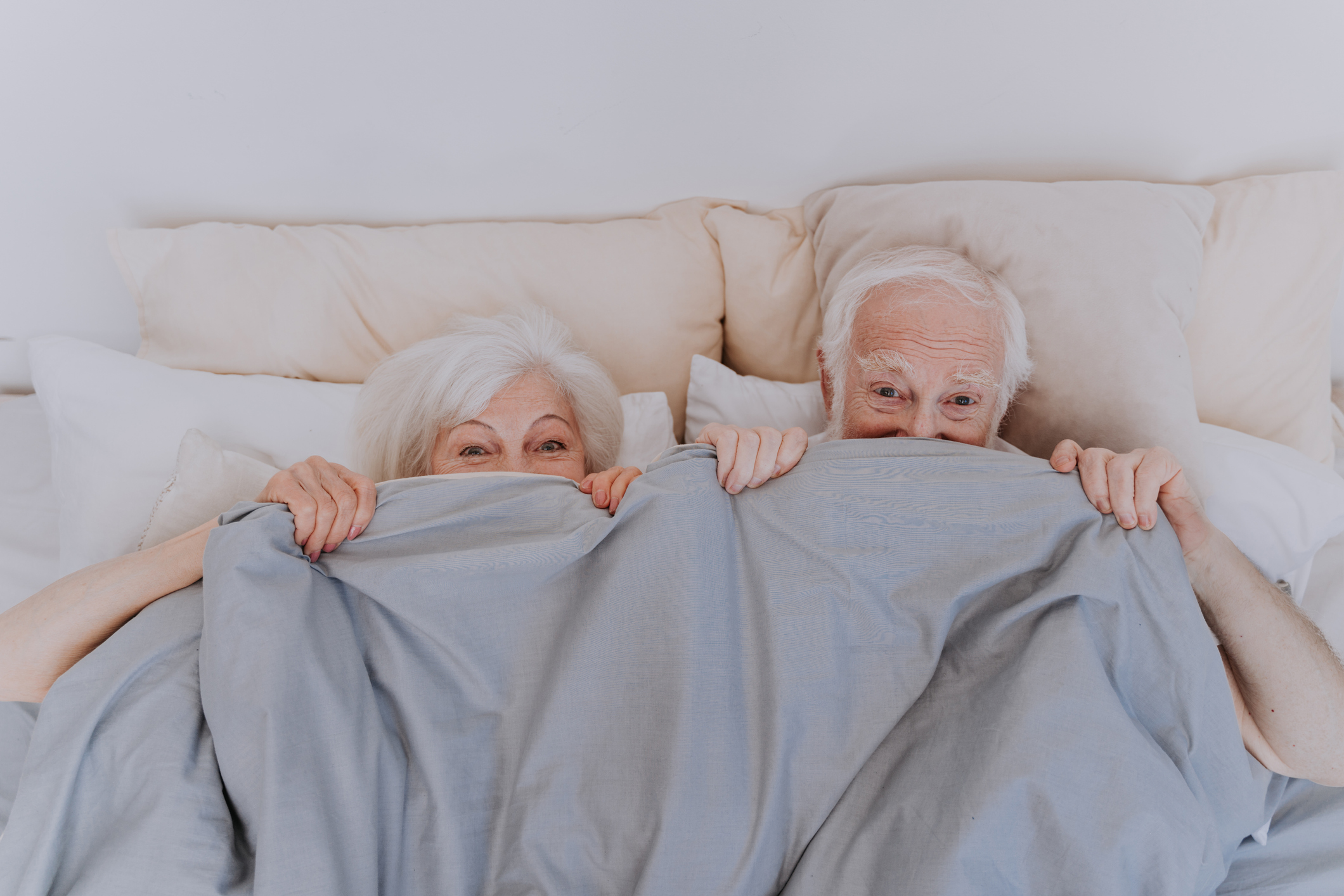 Beautiful senior couple enjoying time together at home - Romantic moments at home, elderly couple in bed needs to rekindle their sex life