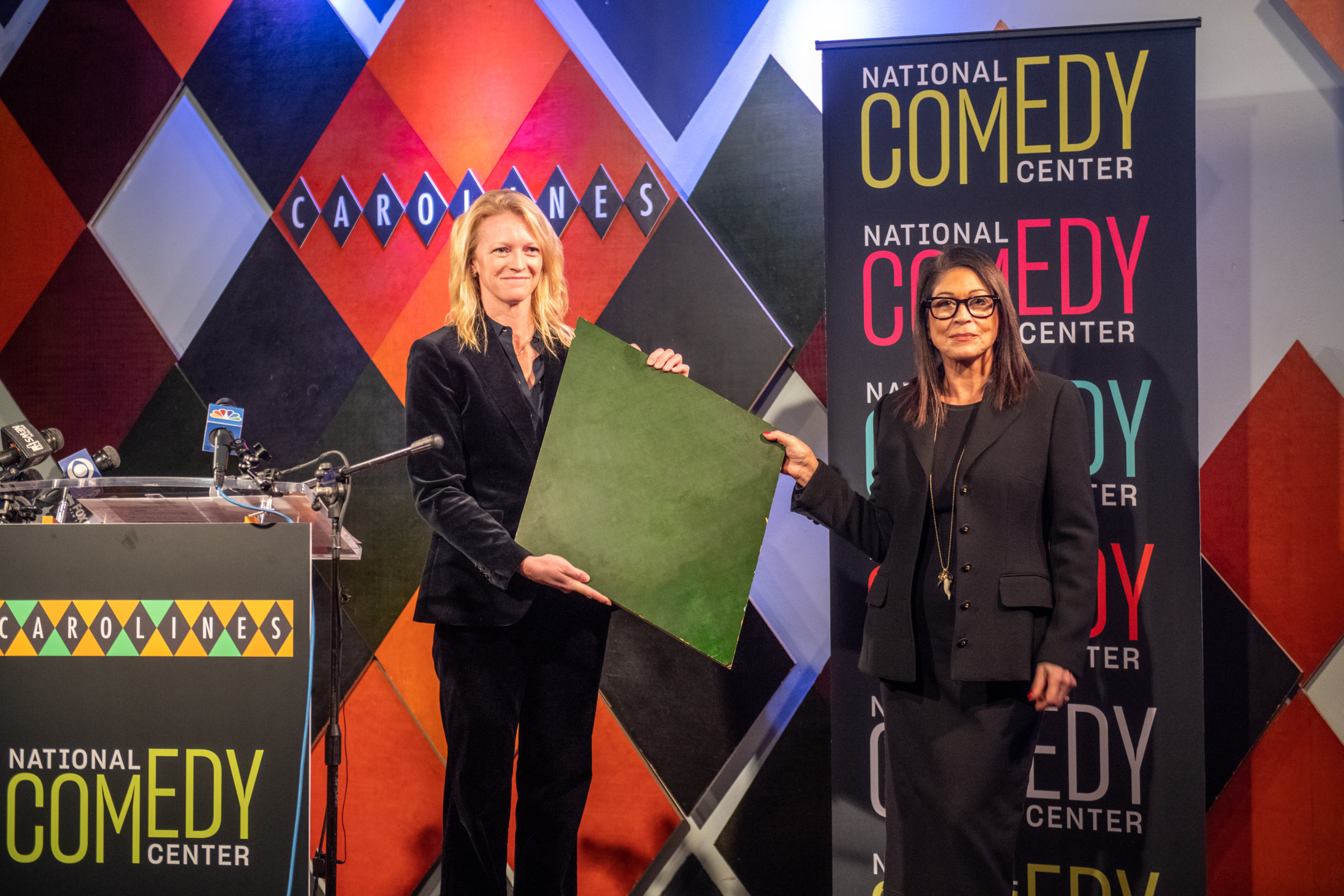 Caroline Hirsch presents Journey Gunderson with an iconic harlequin from her Carolines on Broadway comedy club