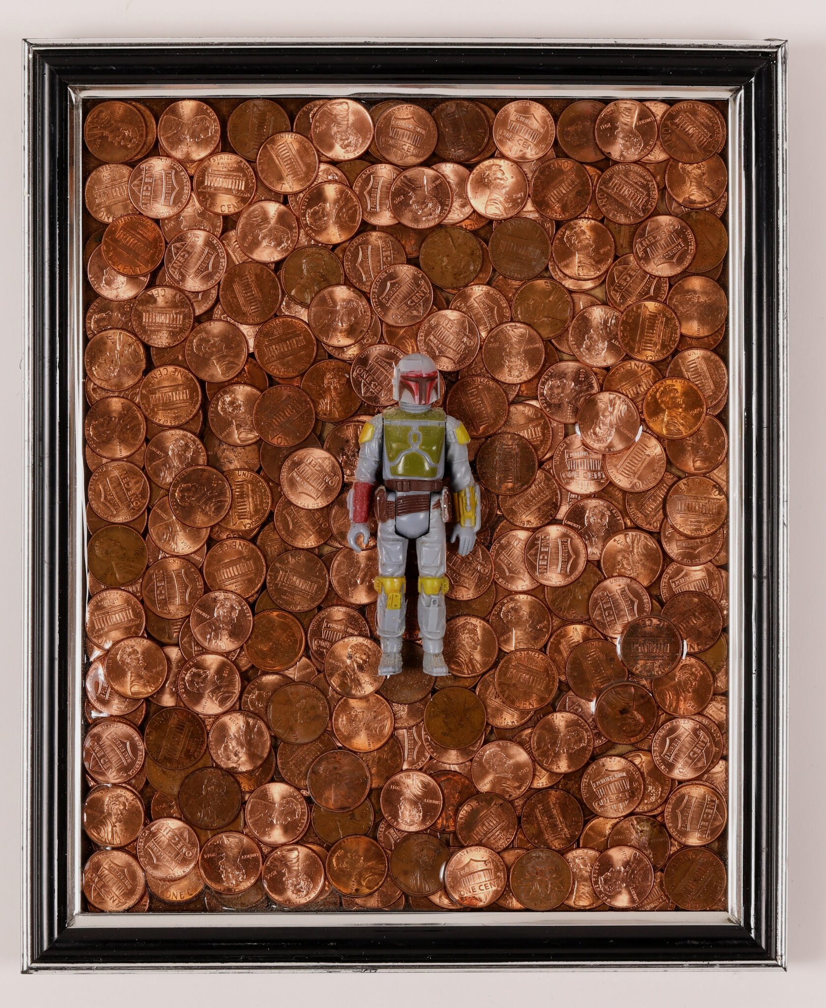 Rossa Cole's "Boba Fett in the Shine of Obsolescence" 2018 9Wx11H found frame, pennies, Boba Fet, epoxy resin